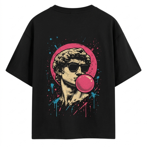 “Man wearing a black oversized Akido graphic t-shirt featuring a retro-style statue illustration with sunglasses and pink bubble gum artwork on the back, standing against a gray concrete wall.”
